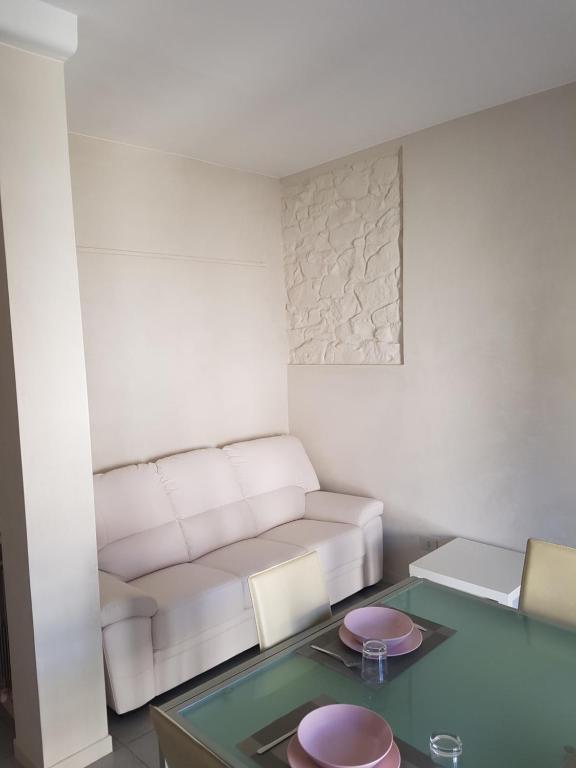 een woonkamer met een witte bank en een glazen tafel bij Casa Anna in Arezzo