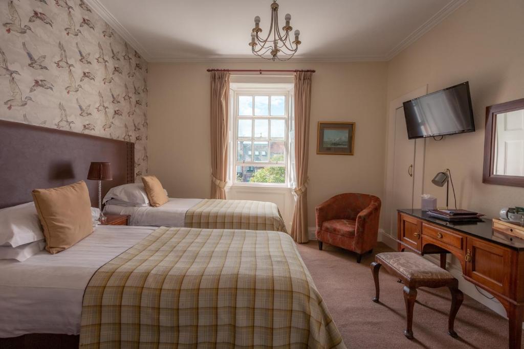 um quarto de hotel com duas camas e uma secretária e uma televisão em The Albany St Andrews em St Andrews