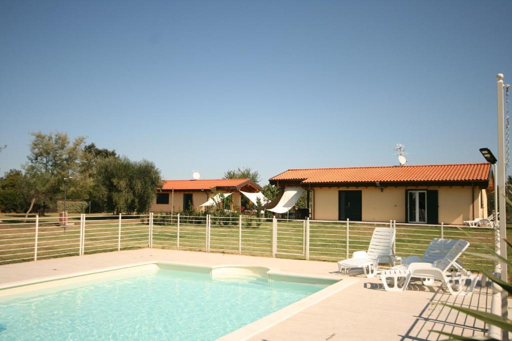 una piscina con due sedie e una casa di Due casette con Piscina a Castagneto Carducci