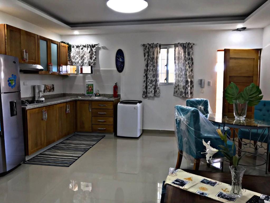 a kitchen with a refrigerator and a table with chairs at Fully Equipped New 1br Apt–dt–2mins To Beach in Sosúa