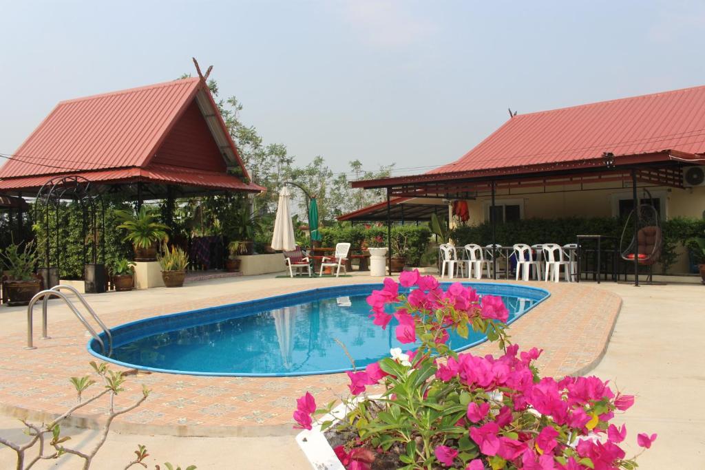 a swimming pool with pink flowers in front of a house at 1 Double bedroom apartment with Pool and extensive Kitchen diningroom in Ban Sang Luang