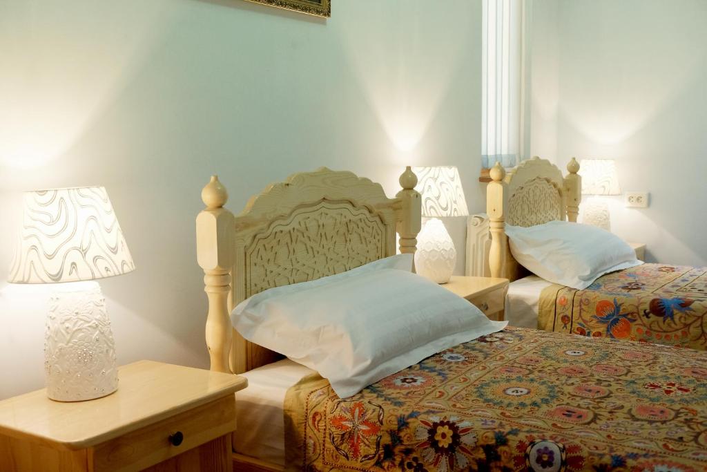 Un dormitorio con 2 camas y una mesa con lámparas. en Ismail, en Bukhara