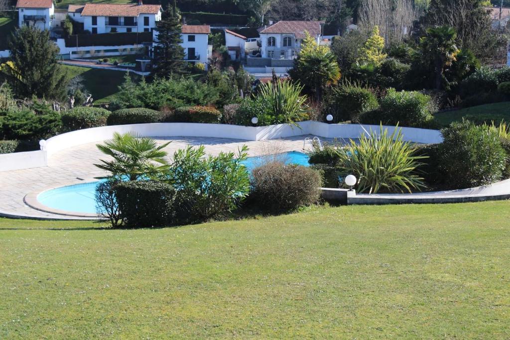 a swimming pool in a garden with bushes and trees at IDUSKIA GRAND STANDING ET VUE PANORAMIQUE in Ciboure