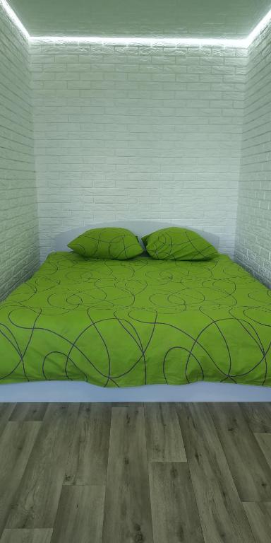 Bett mit grüner Bettwäsche und Kissen in einem Zimmer in der Unterkunft Студія з сучасним ремонтом in Kiew