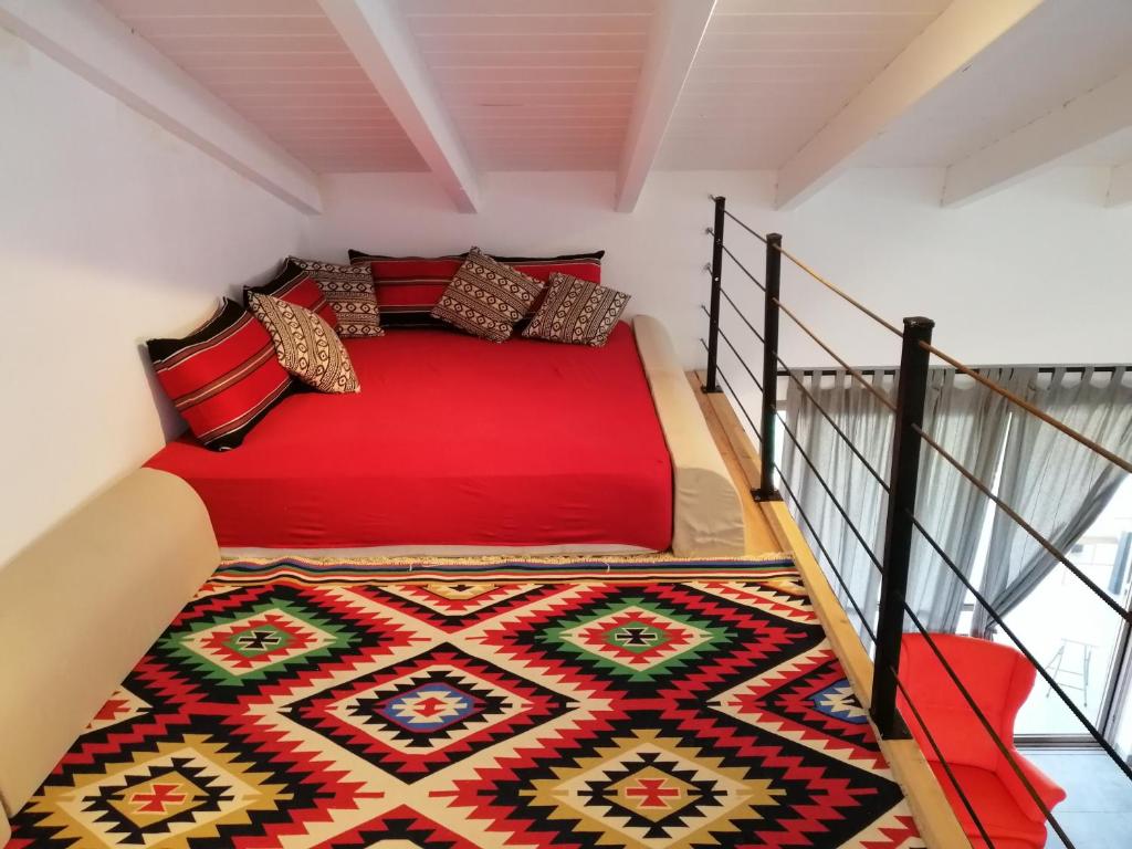 a bedroom with a red bed and a carpet at Villa Bougainvillea in Ashalim