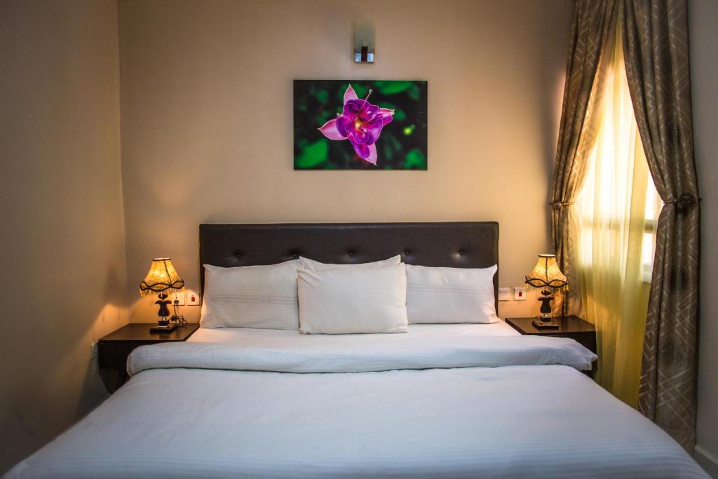 a bedroom with a large white bed with two lamps at Twenty Hotel in Kaduna