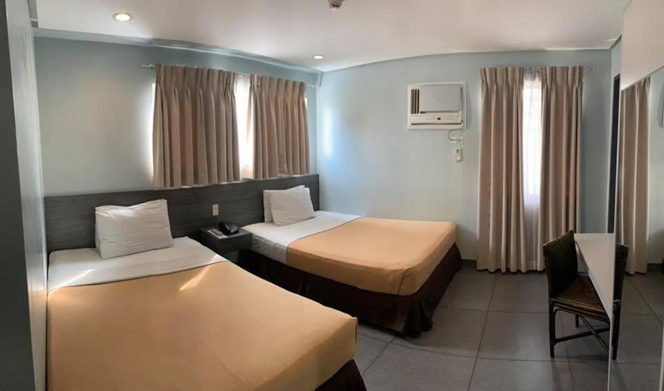 ein Hotelzimmer mit 2 Betten und einem Stuhl in der Unterkunft Cebu R Hotel Mabolo in Cebu City