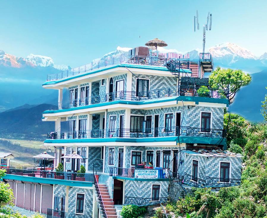 a large house on top of a hill with mountains at Lake View Lodge Sarangkot in Pokhara