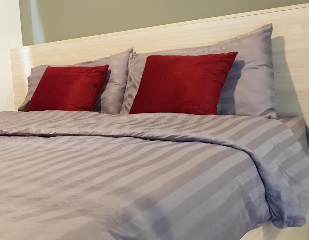 ein Bett mit zwei Kissen und zwei roten Kissen in der Unterkunft Room for rent_66819474542 in Phra Nakhon Si Ayutthaya