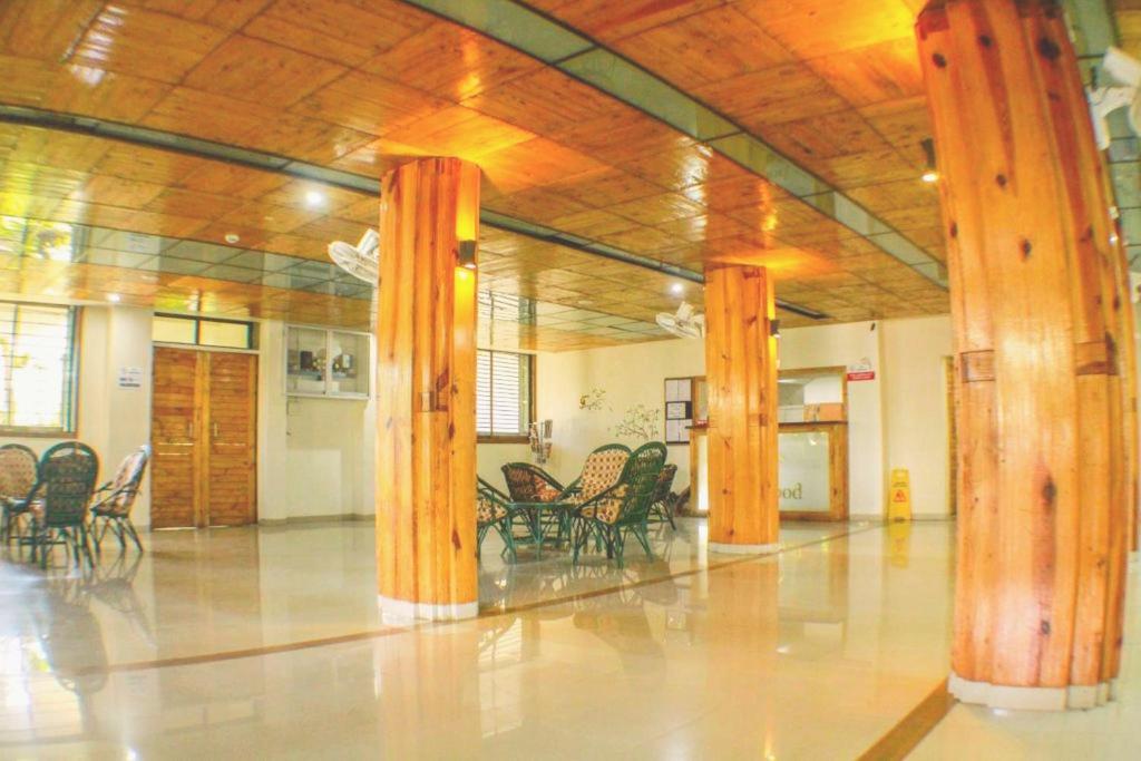 una grande stanza con colonne e sedie in legno di Rainwood Residency a Lonavala
