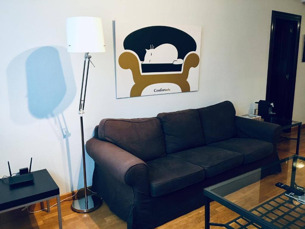 ein Wohnzimmer mit einem braunen Sofa und einem Stuhl in der Unterkunft Apartamentos Confortarte in Oviedo