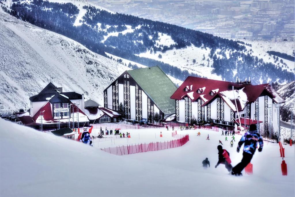 a group of people in the snow in front of a lodge at Dedeman Palandoken Resort Hotel in Erzurum