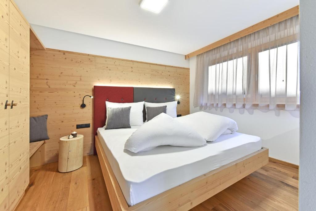 een slaapkamer met een groot bed met witte kussens bij Forchnerhof -Appartement Dolomitenblick in Rodengo