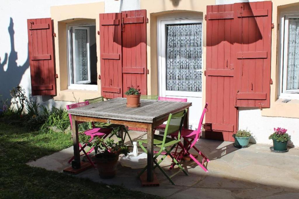 een tafel en stoelen voor een huis met rode luiken bij APPARTEMENT VILLA MERCEDES in Saint-Jean-de-Luz