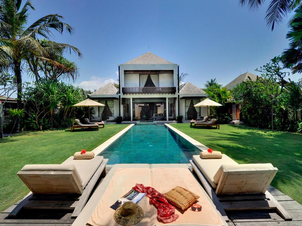 a villa with a swimming pool and a house at Majapahit Beach Villas by Nakula in Ketewel