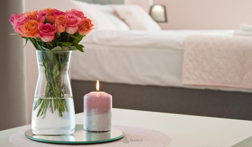 a candle and a vase with flowers on a table at Villa Bianco in Międzyzdroje