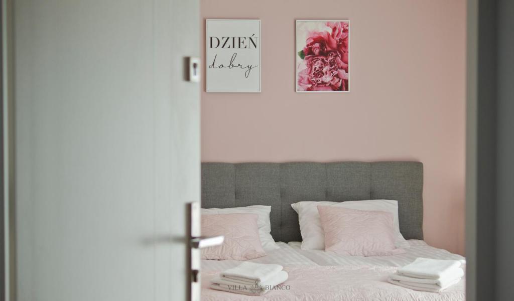 1 dormitorio con 1 cama con almohadas rosas y blancas en Villa Bianco, en Międzyzdroje