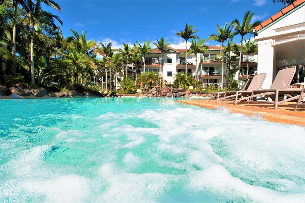 uma grande piscina com cadeiras e palmeiras em Grande Florida Beachside Resort em Gold Coast