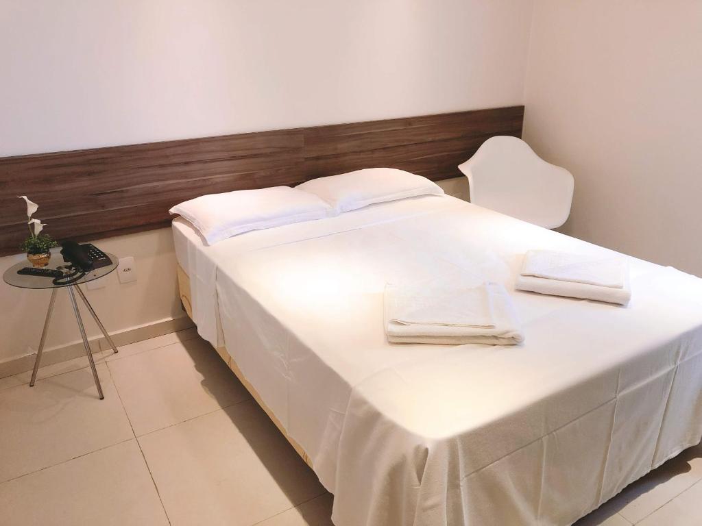 uma grande cama branca com lençóis brancos e uma mesa em Angra Praia Hotel em Fortaleza