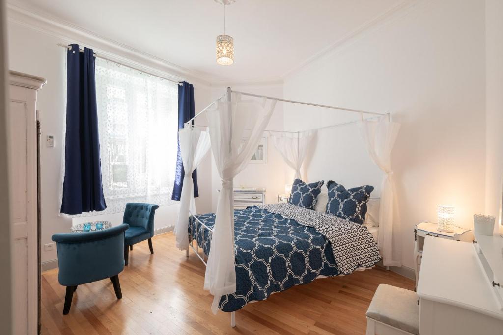 ein Schlafzimmer mit einem Himmelbett und einem blauen Stuhl in der Unterkunft Le Beau Rivage in Nizza