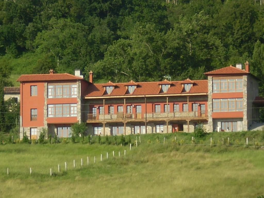 a large building in a field next to a field at Escuelas De Fuentes in Villaviciosa