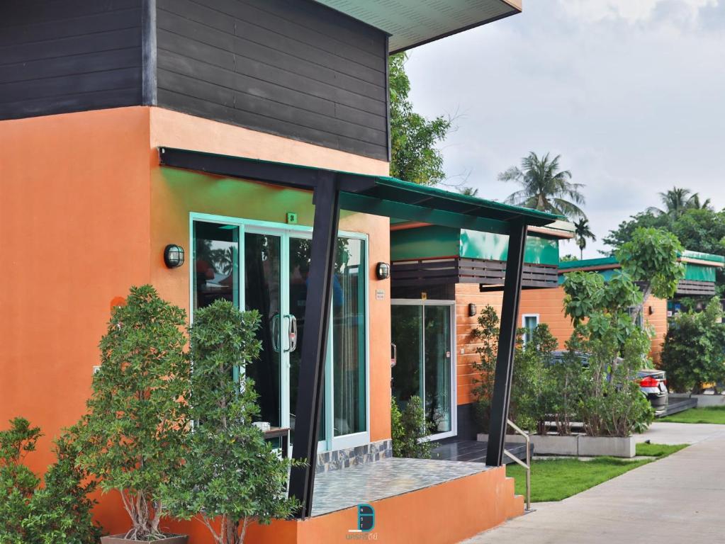 un edificio naranja y negro con árboles delante de él en Nawamit Home Garden, en Nakhon Si Thammarat