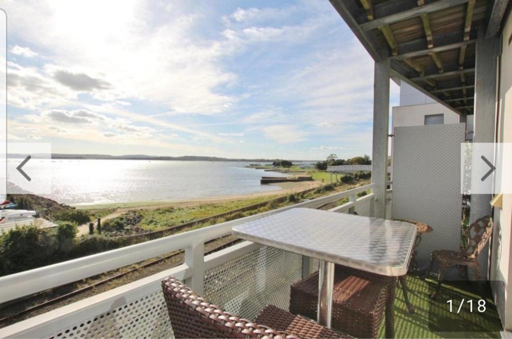 balcón con mesa, sillas y vistas al agua en island reach en Poole