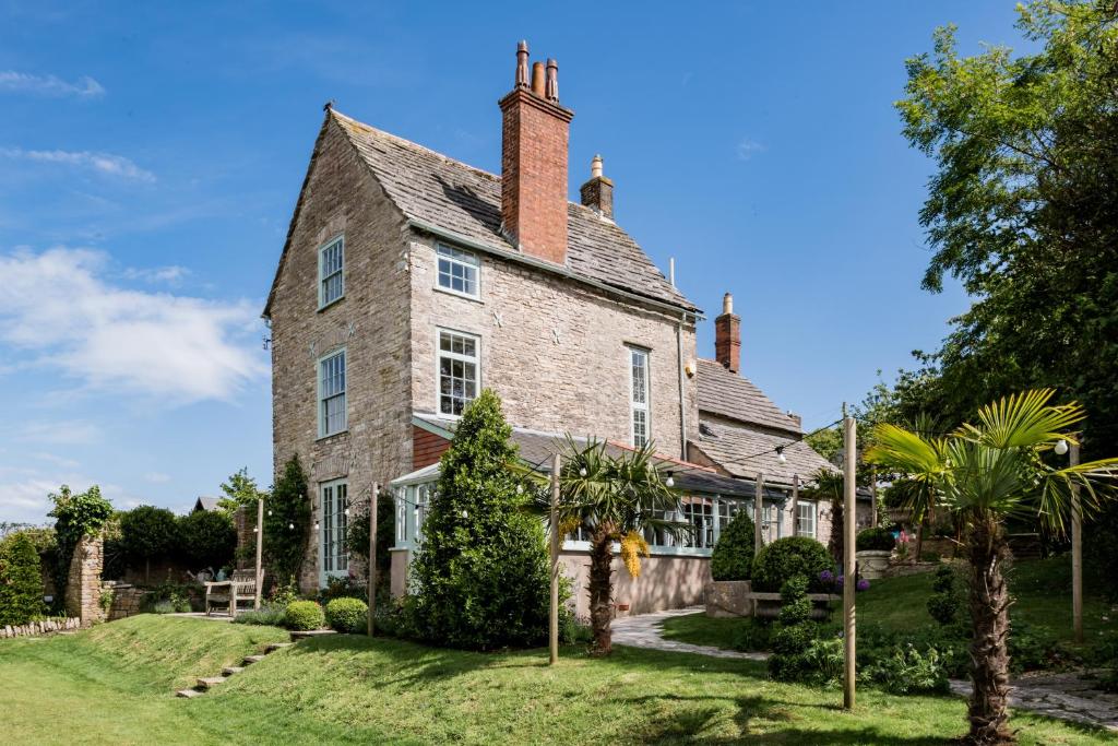 uma velha casa de tijolos com árvores em frente em Magnificent Clarence cottage! em Swanage