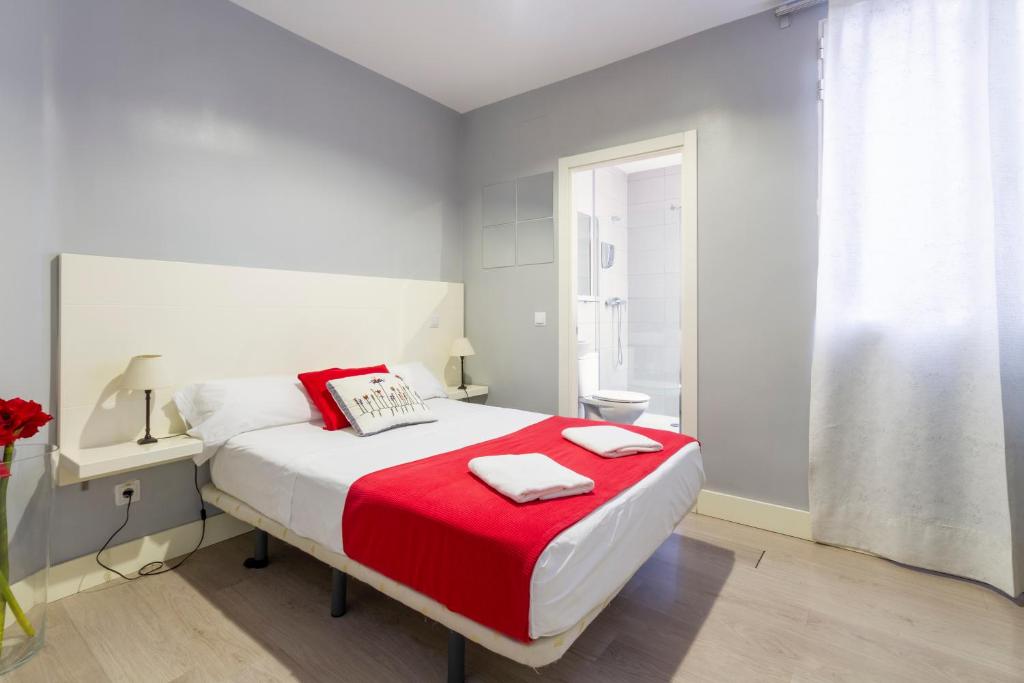 um quarto com uma cama com um cobertor vermelho em 8Rooms Madrid em Madri