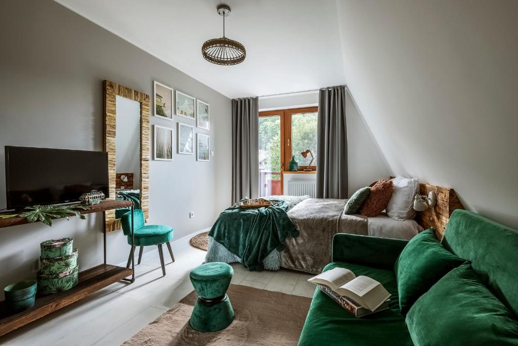 ein Wohnzimmer mit einem grünen Sofa und einem Bett in der Unterkunft LOFT 85 in Szczyrk