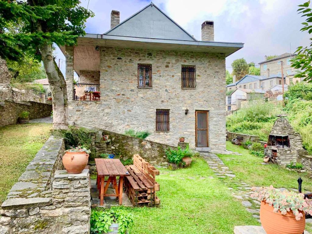 une maison en pierre avec une table en bois devant elle dans l'établissement Πέτρινο παραδοσιακό σπίτι "Χιονάτη", à Nymfaio