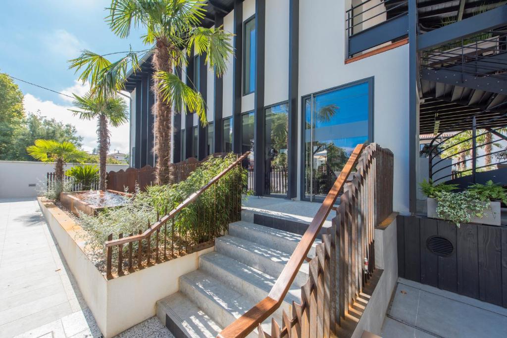 un escalier menant à un bâtiment avec des palmiers dans l'établissement L'Anderenis Boutique Hôtel, à Andernos-les-Bains