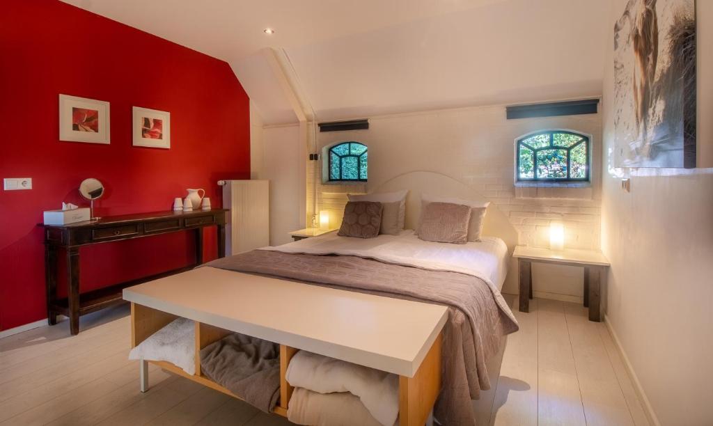 Un dormitorio con una cama con paredes rojas y un escritorio. en Drentse krent, en Veeningen