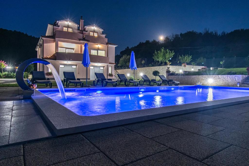 a swimming pool in front of a house at night at Green Paradise Estate Trilj in Trilj