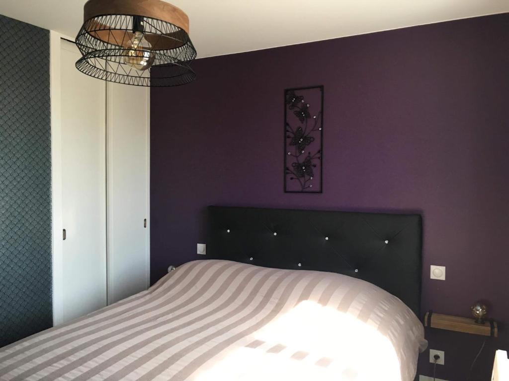 een slaapkamer met een bed en een paarse muur bij L’Edaines in Bagnoles de l'Orne