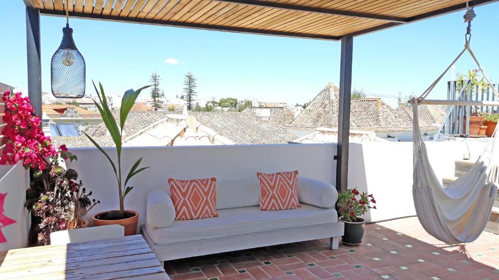 eine weiße Couch auf einer Terrasse mit Hängematte in der Unterkunft Calcada Guesthouse in Tavira