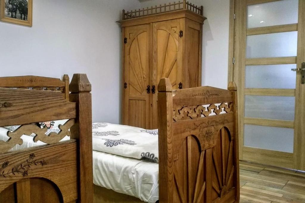 a bedroom with two bunk beds and a wooden cabinet at Zakodomki Apartament Tatrala in Kościelisko