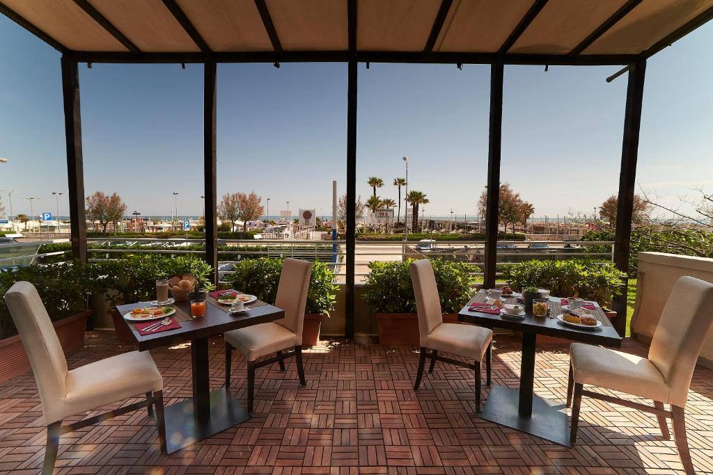 a patio with two tables and chairs and windows at Alisei Palace Hotel in Rimini