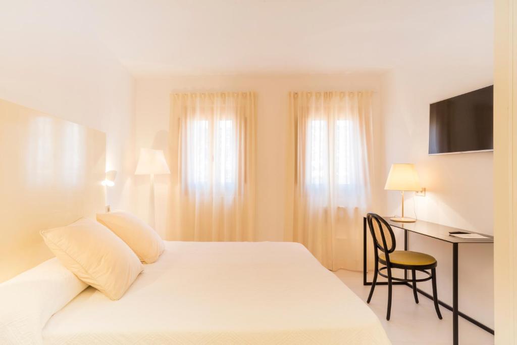 a hotel room with a white bed and a desk at Fonda Llabres Boutique in Alcudia