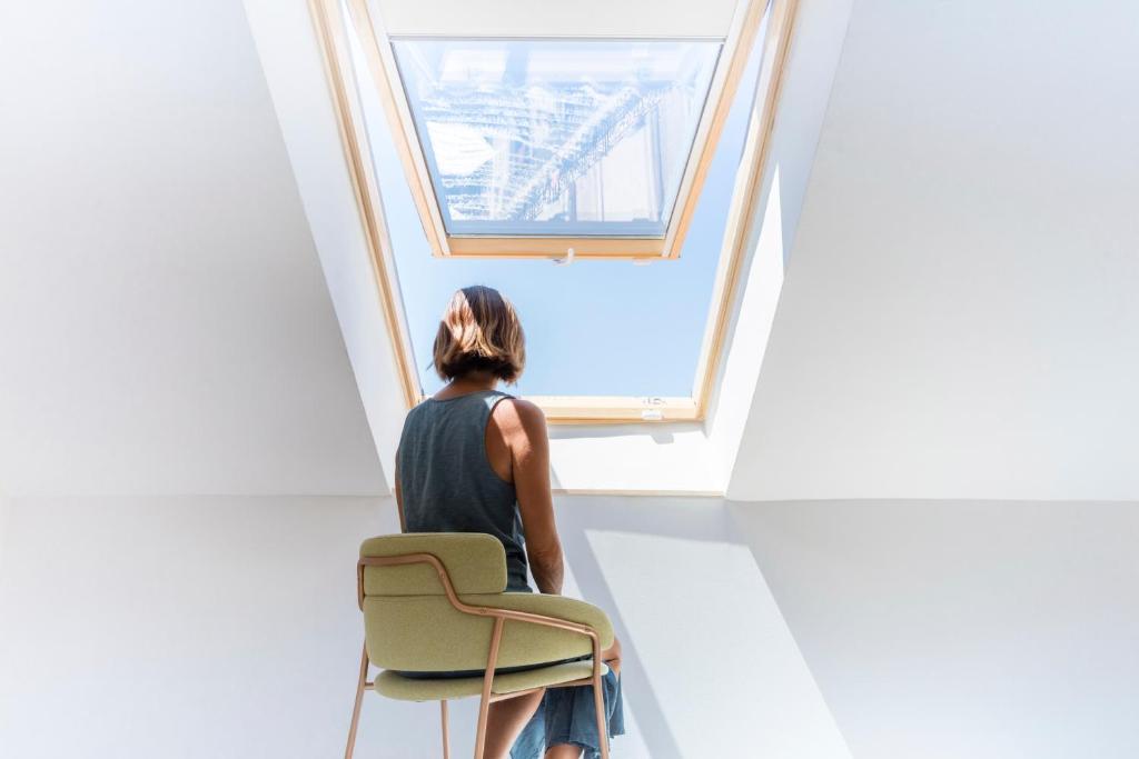 a woman sitting on a chair looking out of a window at Fonda Llabres Boutique in Alcudia
