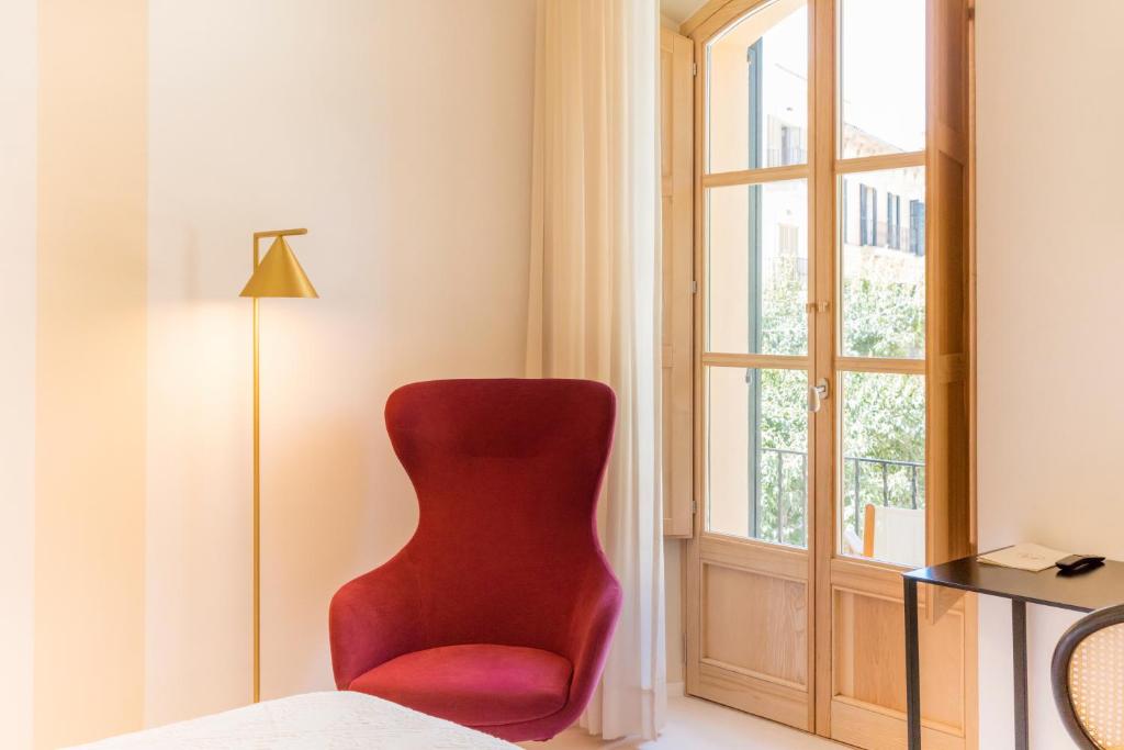 a red chair in a room with a window at Fonda Llabres Boutique in Alcudia