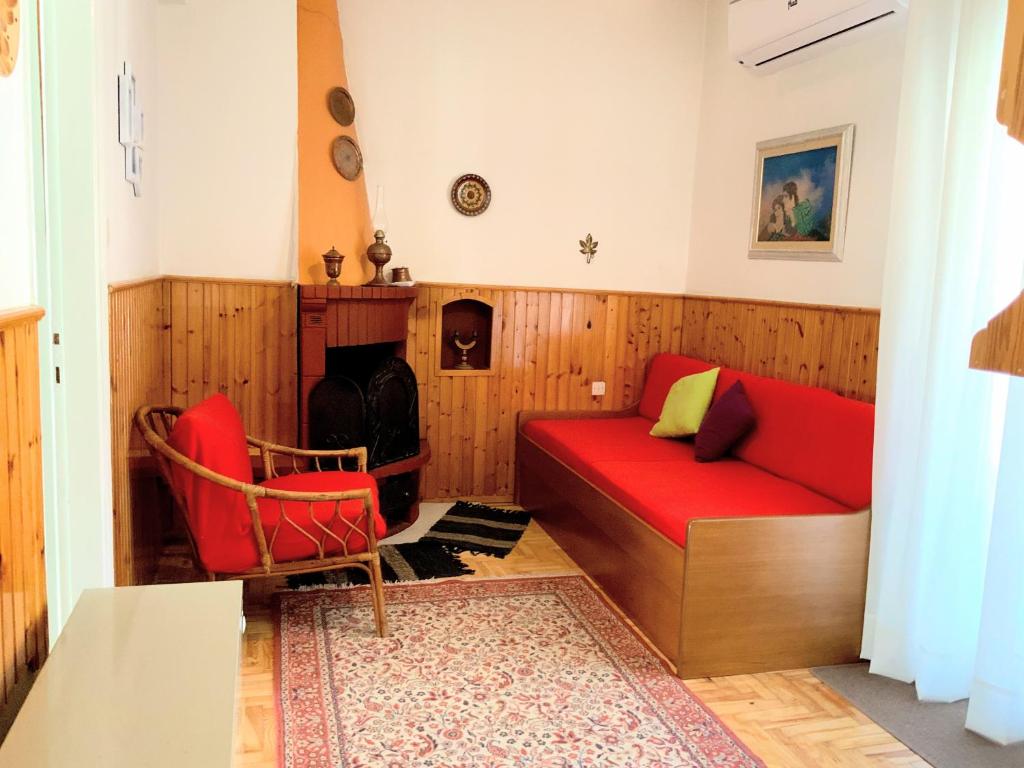 a living room with a red couch and a fireplace at Traditional penthouse with mountain view in Grevena