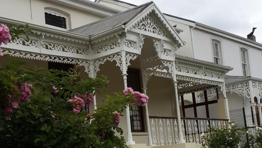 a white house with white trim and pink flowers at House On Plein in Paarl