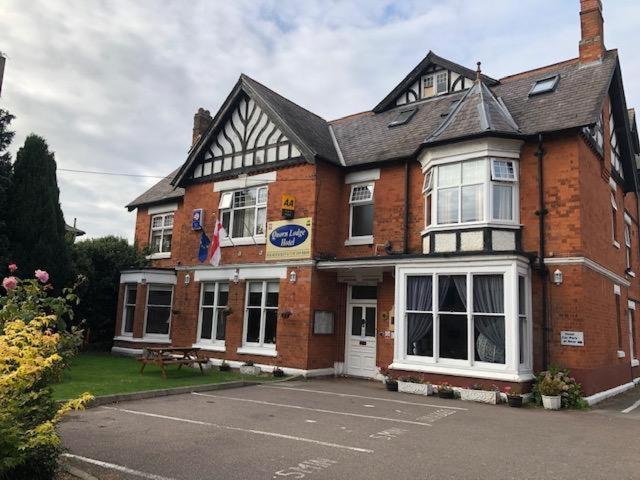 a large brick building with a bench in front of it at The Quorn Lodge Hotel in Melton Mowbray