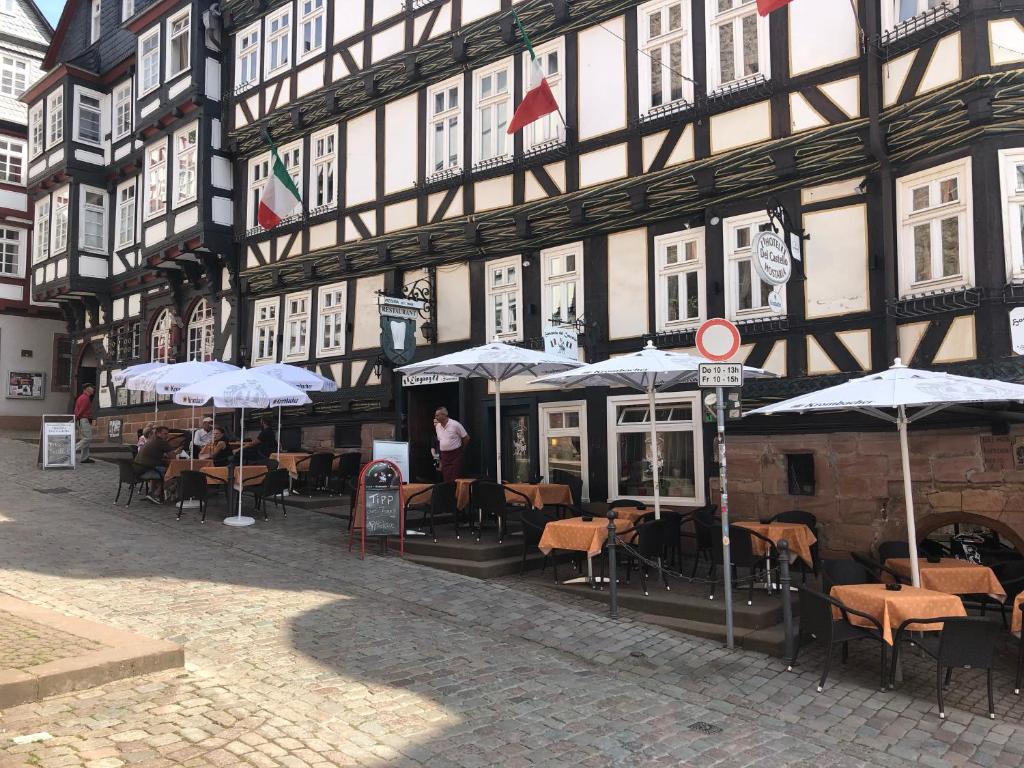 ein Gebäude mit Tischen und Sonnenschirmen davor in der Unterkunft Hostaria del Castello in Marburg an der Lahn