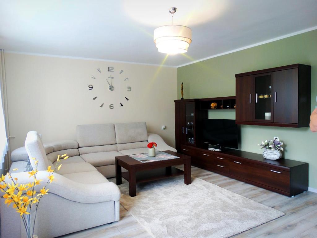 a living room with a couch and a clock on the wall at Apartament Zacisze in Jelenia Góra