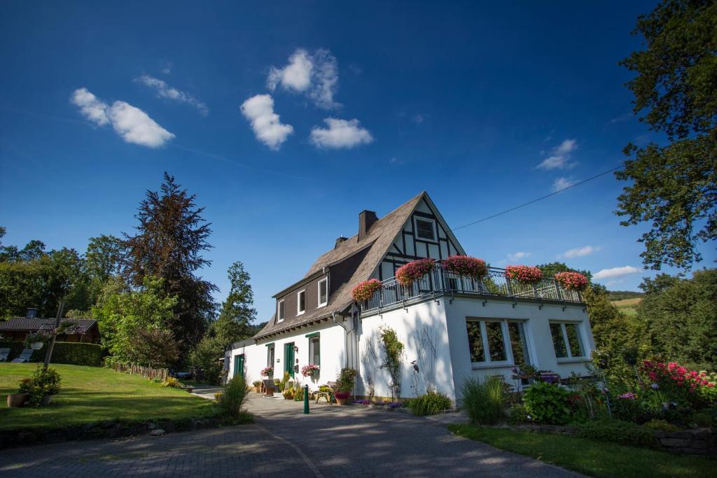 una casa blanca con flores en el balcón en Pension Haus am Walde en Schmallenberg