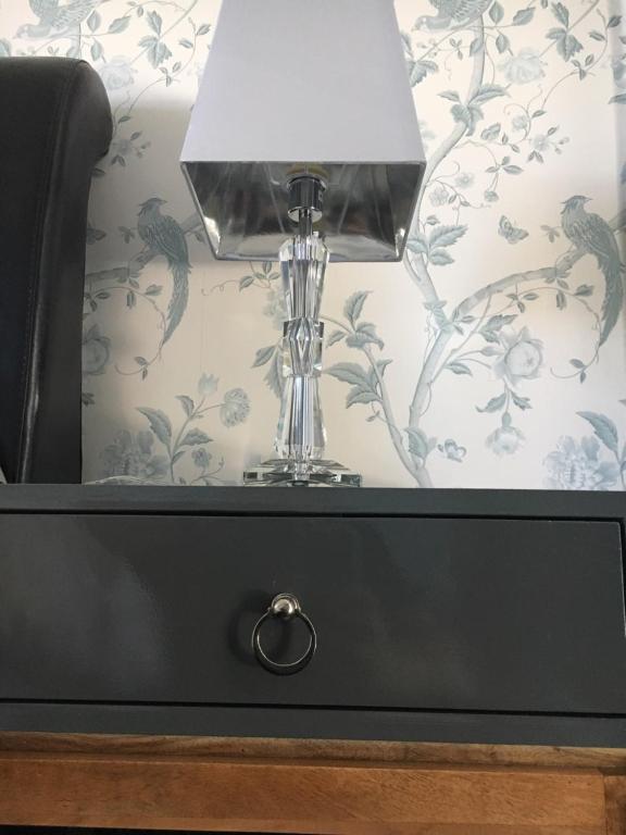 a table with a lamp on top of a black drawer at The Carrick in Portrush