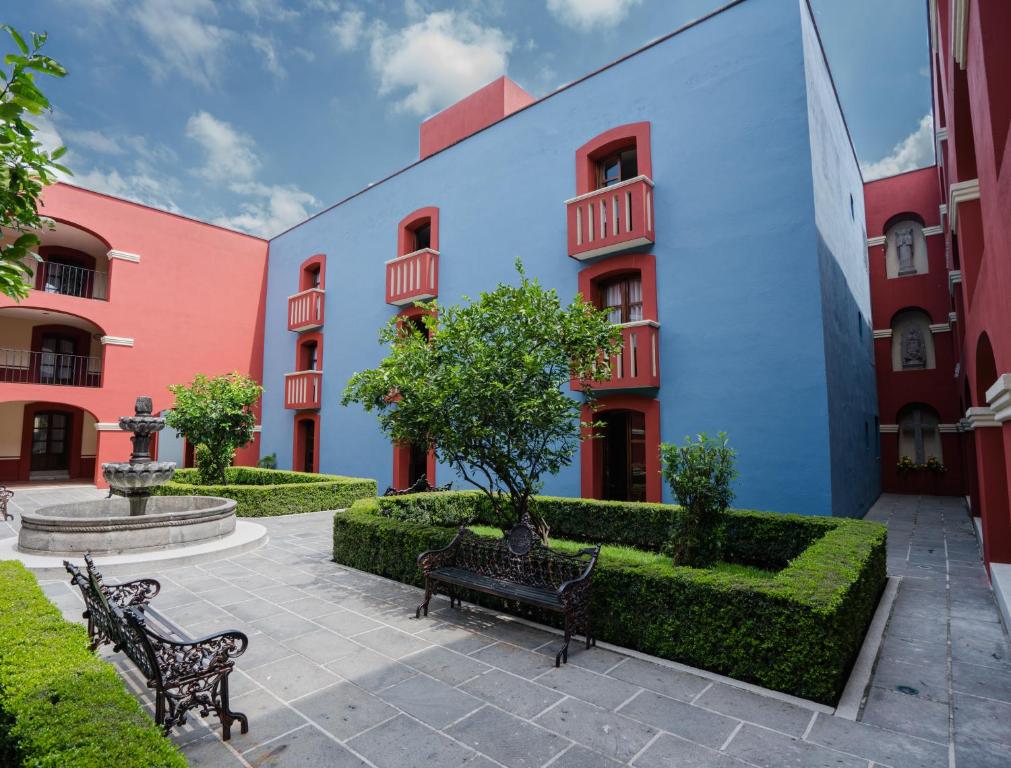 un patio con bancos frente a un edificio en Hotel Real de Naturales, en Cholula