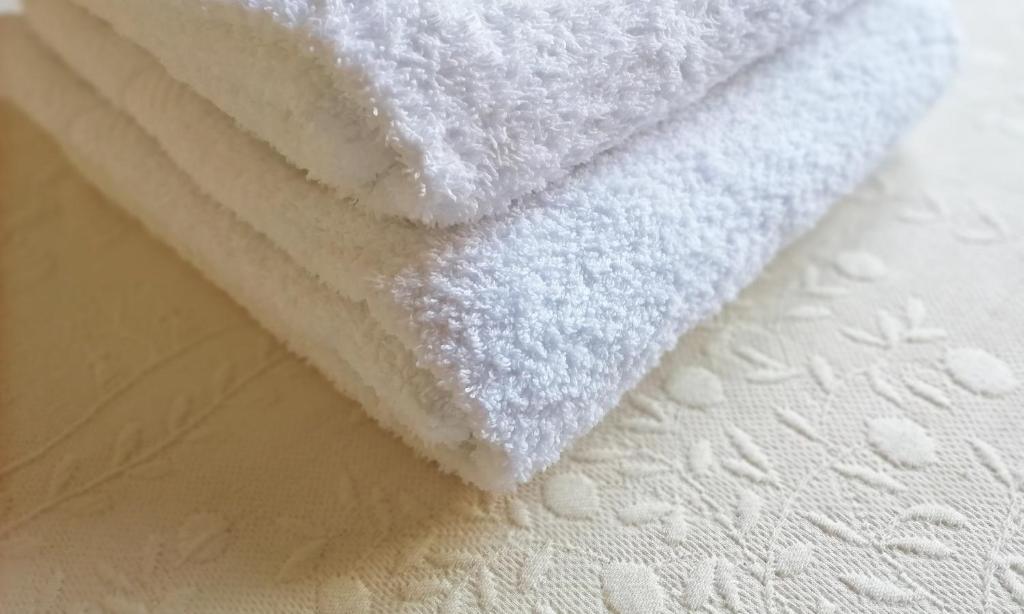 stos białych ręczników siedzących na łóżku w obiekcie L'Alloggio di Anna Maria Mansarda con bagno privato w mieście Empoli